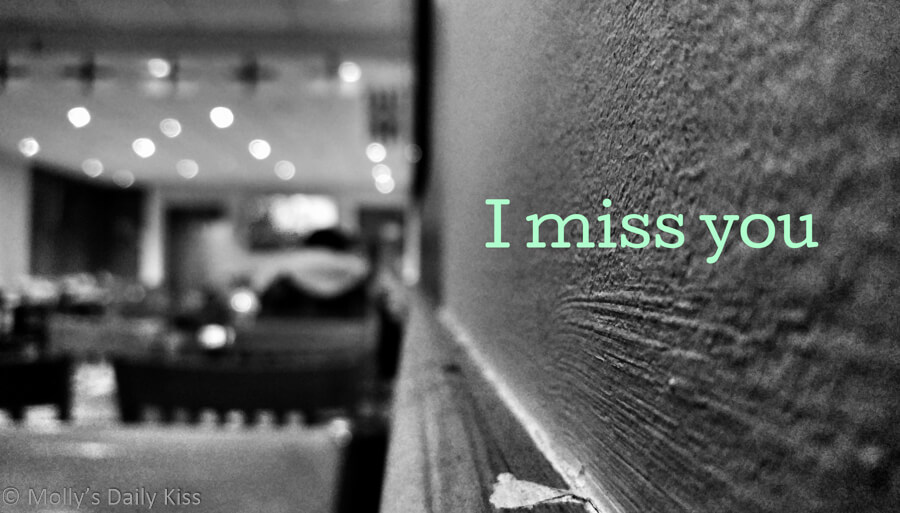 Man sitting alone in cafe on the wall it says I miss you