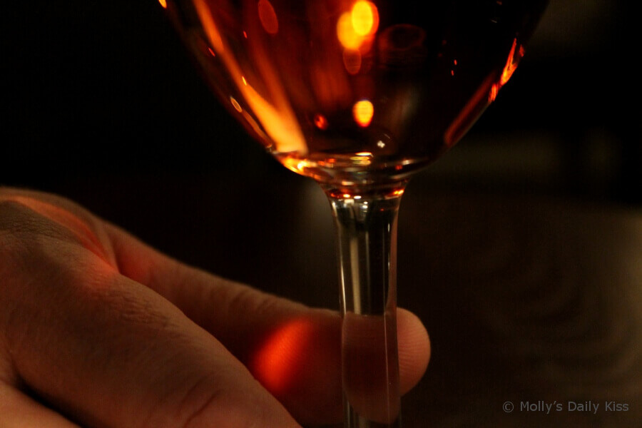 Mans fingers on stem of wine glass