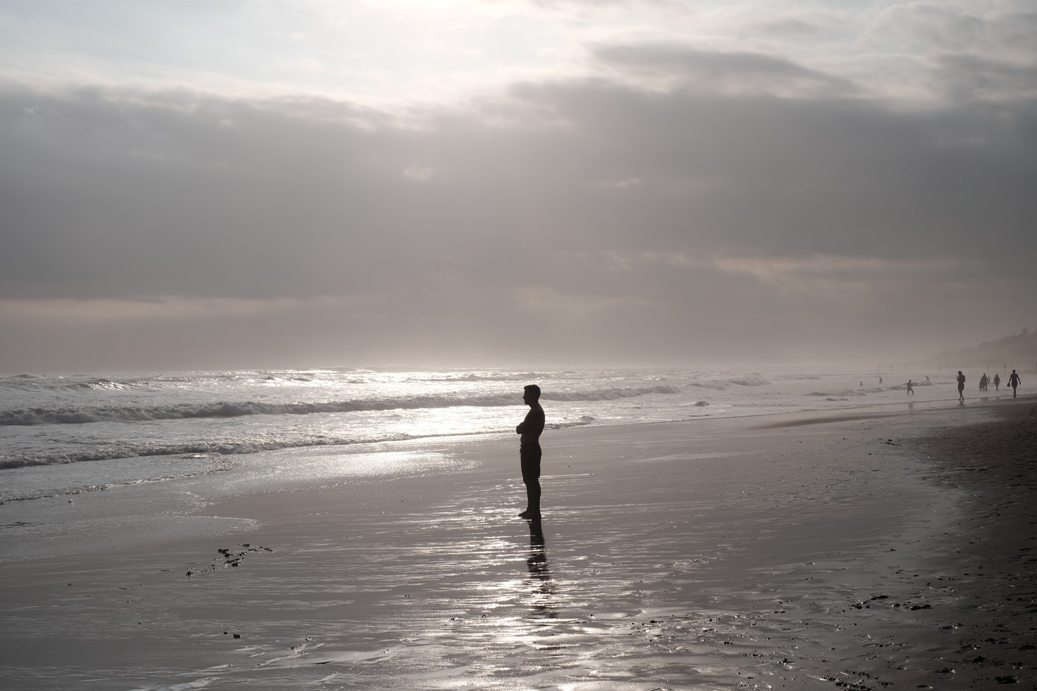 Man standing on the beach looking out to sea